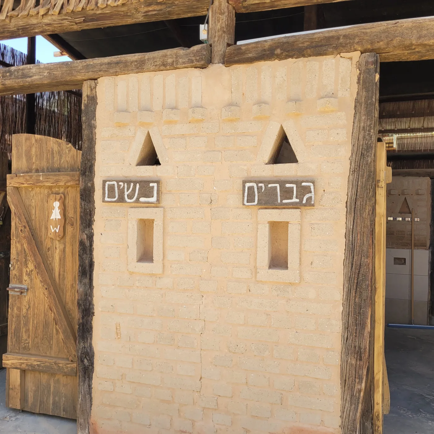 שילוט גברים ונשים על קיר לבני הבוץ בכניסה לשירותים